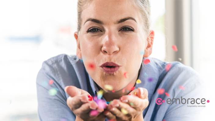 Vrouw blaast confetti uit haar handen naar voren.