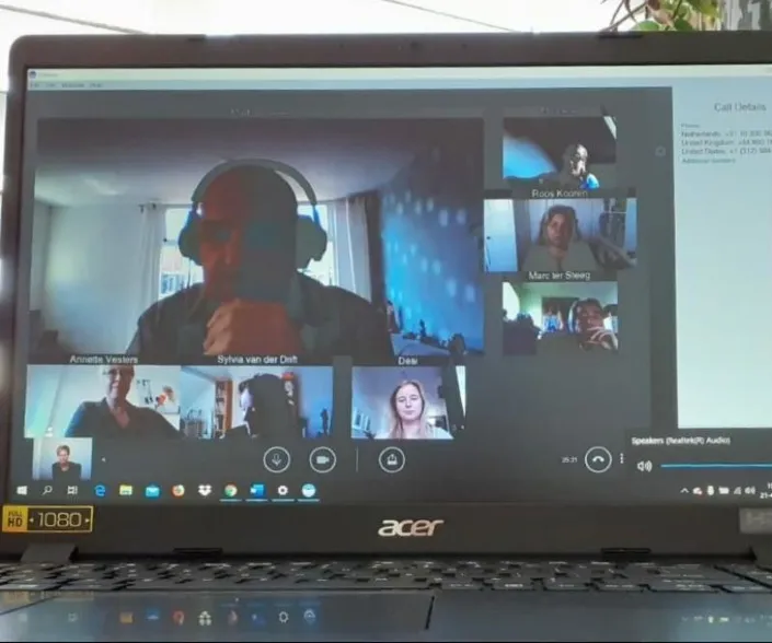 Laptopbeeldscherm met een online videogesprek via Skype, waarbij meerdere deelnemers zichtbaar zijn in verschillende vensters.