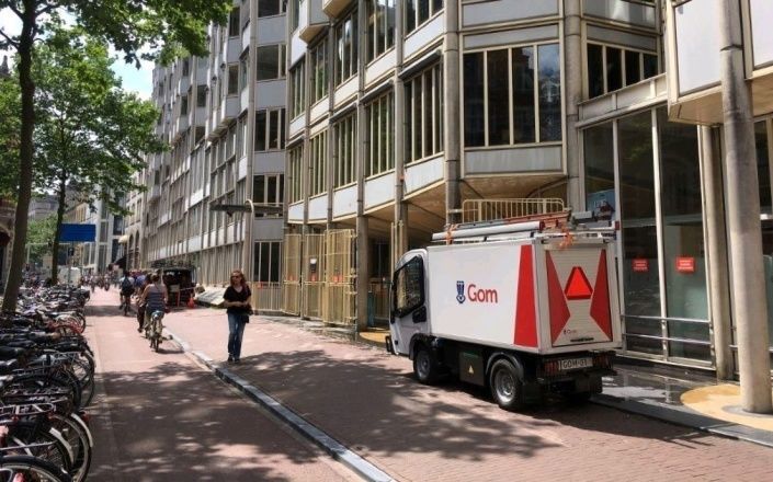 Een kleine elektrowagen in de binnenstad van Amsterdam voor de glasbewassing