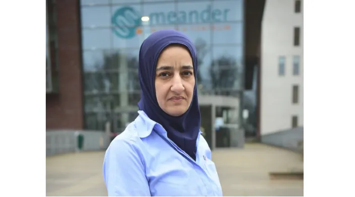 Ziekenhuisschoonmaakster met hoofddoek staat buiten voor de ingang van het Meander Medisch Centrum, symbool voor haar werk in de eerste linie van de coronabestrijding.