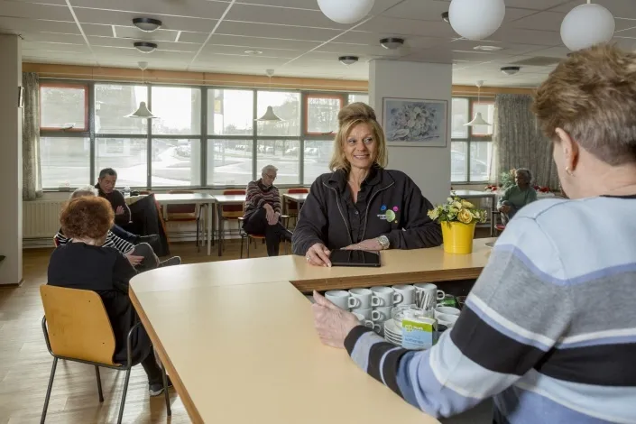 Een huismeester van Gom in gesprek met bewoners in een gemeenschappelijke ruimte, als vertrouwd aanspreekpunt en toezichthouder binnen het complex.