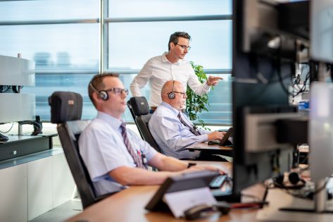 Twee mannen kijken op een computerscherm om op afstand bruggen, wegen en sluizen te bedienen.