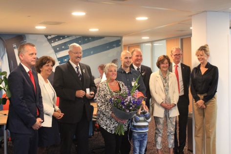 Vijf mannen en vier vrouwen staan op het hoofdkantoor van Trigion met elkaar op de foto om het jubileum van een medewerker te vieren.