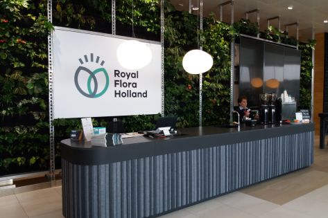 Afbeelding van de receptie in de vorm van een lange bar met daarachter een scherm met de naam Royal Flora Holland