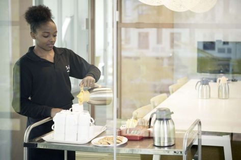 een studente schenkt koffie vanuit een koffiekan in