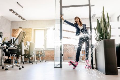 Vrouw in zakelijke kleding rolt op rollerskates binnen op kantoor.