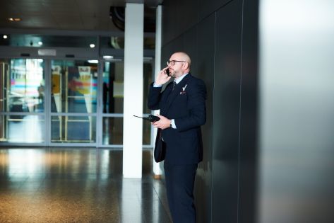 Mannelijke beveiliger loopt in uniform rond en praat in een telefoon.