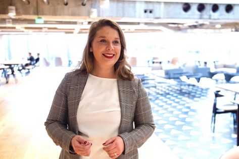 Laura Stein poseert in de aankomsthal van een bedrijfspand.