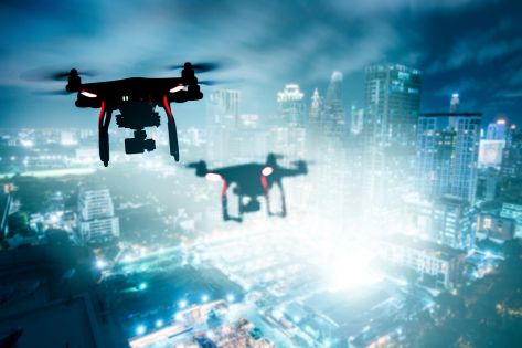 Twee drones die in de avond vliegen over een complex.