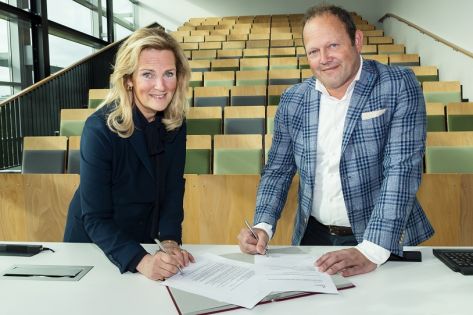 Monique Peels, Directeur Huisvesting & Facilitair Zaken (Fontys) en Barry van de Velde, Sales directeur (Gom) ondertekenen het schoonmaakcontract in een collegezaal