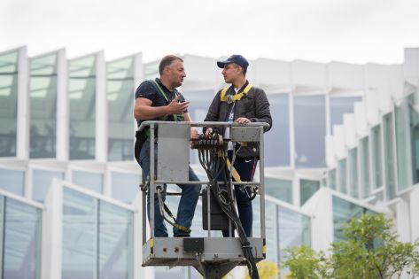 2 mannen staan in het bakje van een hoogwerker en praten met elkaar