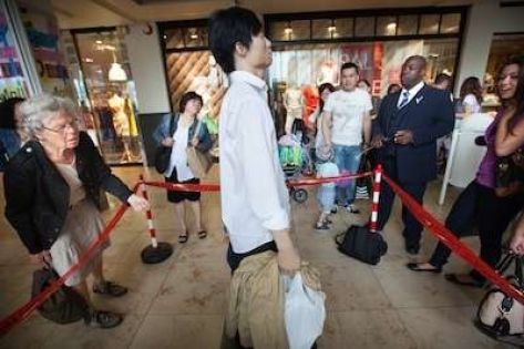 Chinese man staat in de rij en om hem heen staan ander winkelend publiek te wachten.