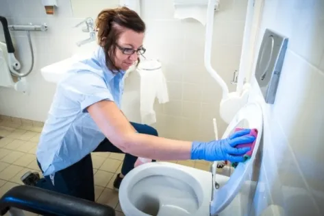 Schoonmaakmedewerker van Gom Zorg maakt een toilet grondig schoon in een sanitaire ruimte van de Radiotherapiegroep Deventer, als onderdeel van 24-uurs schoonmaak met probiotica.