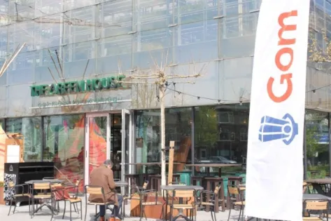 Medewerker van Gom bedient een schrobmachine tijdens het schoonmaken van de vloer in een grote binnenruimte.