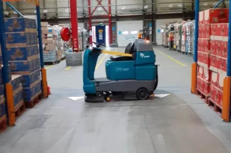 Autonome schrobmachine Tennant T7 AMR rijdt zelfstandig tussen hoge magazijnstellingen in het distributiecentrum van Albert Heijn in Tilburg.