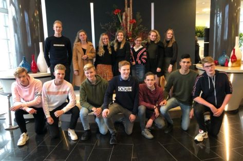 Groep jongeren geposeerd voor een groepsfoto in de hal van het hoofdkantoor van Facilicom Group in Schiedam.