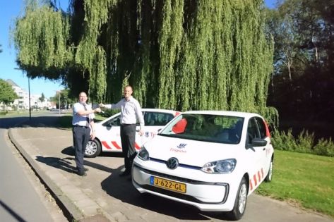 Twee mannen overhandigen elkaar de sleutel van een nieuwe Elektrische auto van Trigion.