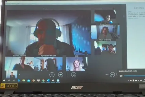 Laptopbeeldscherm met een online videogesprek via Skype, waarbij meerdere deelnemers zichtbaar zijn in verschillende vensters.