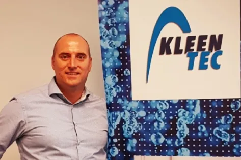Man poseert naast een banner met het logo van KleenTec.